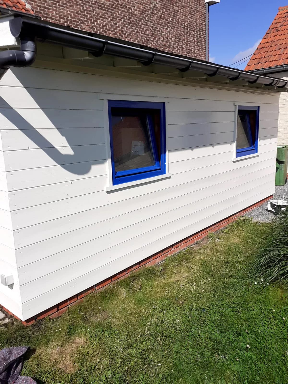Dezelfde aanbouw na het schilderen, wit met blauwe raamkaders